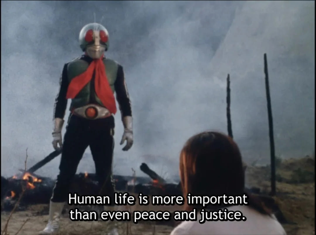 A screenshot of Kamen Rider standing in front of a person, saying to them, “Human life is more important than even peace and justice.”